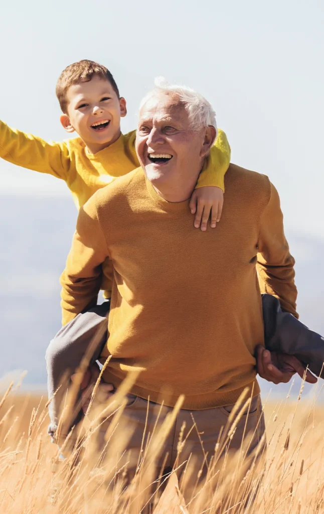 smiling young boy on his grandfathers shoulders life insurance for retirement
